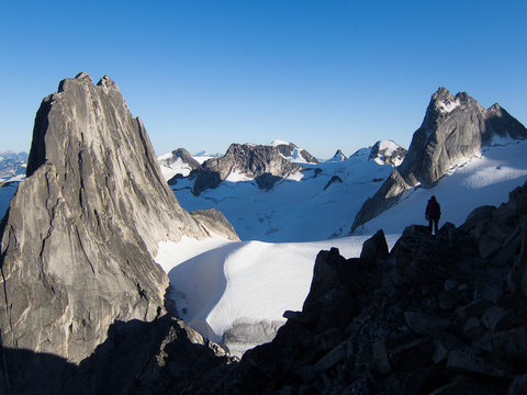 Climber silhouetted against glaciers and mountains.
