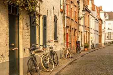 Obraz na płótnie Canvas Bruges, Belgium - October 9, 2014: Typical Belgian street and parked bicycles on foreground