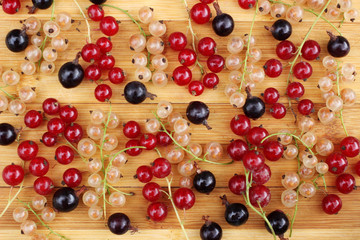 Sprigs of different berries: black currant, red currant and gooseberry on a wooden table.