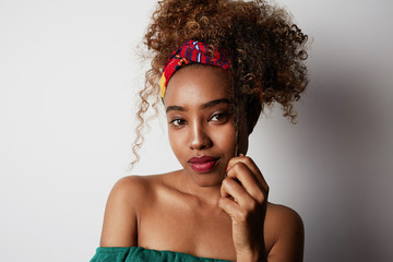 Closeup portrait of a confident young American African girl with long curly hair standing alone against a white background