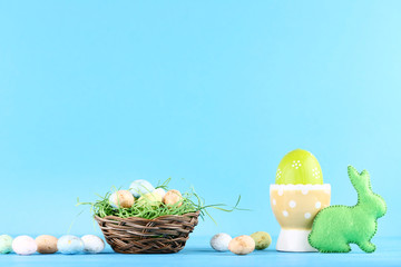 Easter eggs with green fabric rabbit on blue background