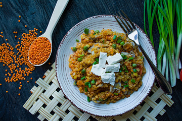 Lentil porridge with vegetables and herbs and fett cheese. Healthy lifestyle. Dietary menu. Dark wooden background. View from above.