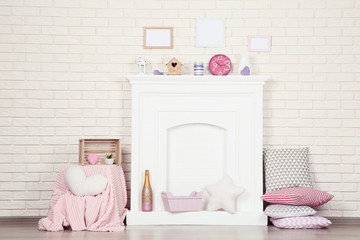 White fireplace with photo frames, round clock, pillows and soft toys