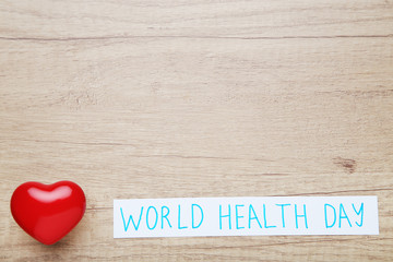Text World Health Day with red heart on wooden table