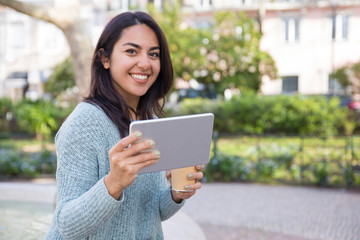 Fototapeta premium Happy woman using tablet computer and holding plastic cup