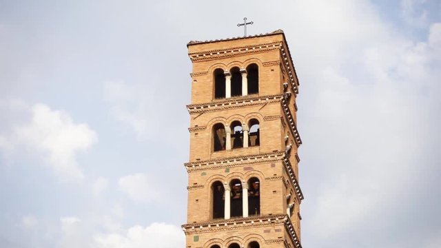 Close up of bell tower of Basilica of Saint Mary in Cosmedin with Mouth of Truth or Bocca della Verita against blue cloudy sky