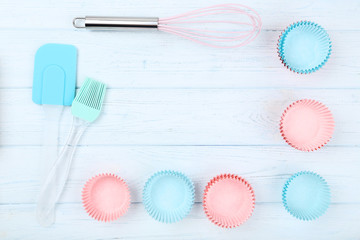 Cupcake cases with kitchen utensils on wooden table