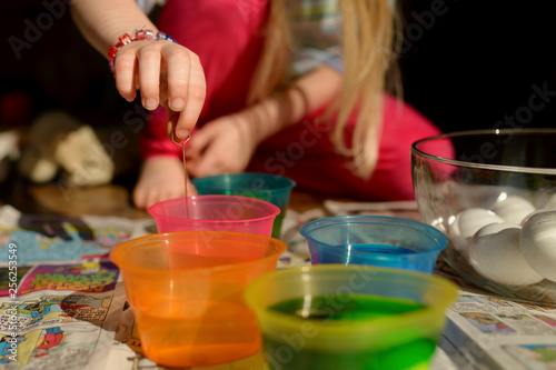 Girl mixing colors in bowl while sitting on floor at home
