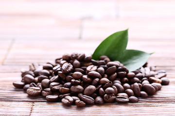 Coffee beans with green leafs on brown wooden table