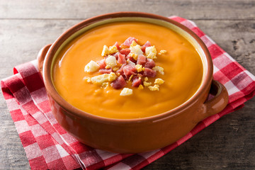 Typical Spanish salmorejo cream with ham and egg on wooden table