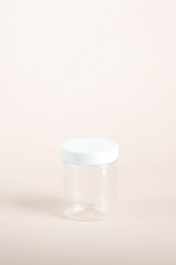 Plastic transparent jar with a white lid for cosmetic cream or gel. Light background. Close-up. Side projection.
