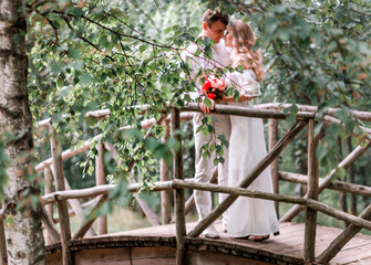 Naklejka na ściany i meble Groom bride posing on a wooden bridge