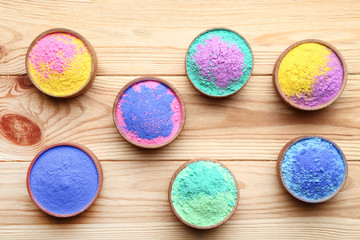 Colorful holi powder in bowls on brown wooden table