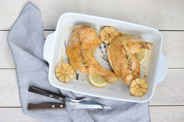 Chicken legs with lemon, thyme and garlic. Chicken legs cooked on the grill. Light wooden background. Close-up. View from above. 