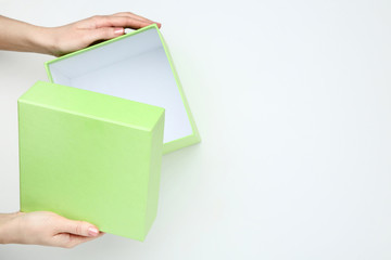 Female hands opening green gift box on white background