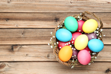 Easter eggs in basket with gypsophila flowers on wooden table
