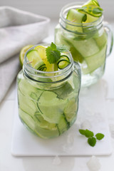 water, drink with lime and cucumber, mint and ice on a white background.