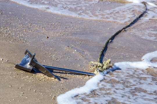 Metal anchor with a tied rope on the sand