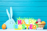 Colorful eggs with wooden rabbit and text Happy Easter on blue background