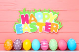 Colorful eggs with text Happy Easter on wooden background