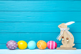 Colorful easter eggs with wooden rabbit on blue background