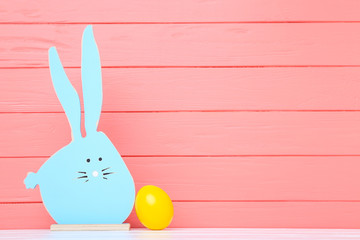 Colorful easter egg with wooden rabbit on coral color background