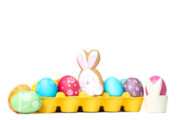 Easter eggs in carton box with gingerbread cookies isolated on white background