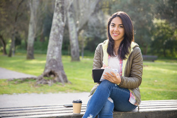 Obraz premium Cheerful mixed race girl planning day while sitting on bench