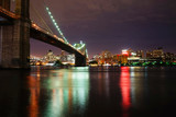 Illuminated Brooklyn Bridge over river against illuminated city