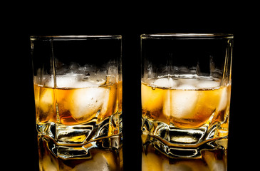 Whiskey with ice close up on a glass table isolated on a black background