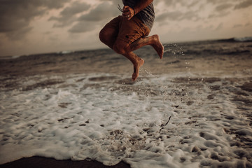 Healthy, fit and american man jumping for joy on a beach during sunset while on vacation. Concept of a happiness, life and wellness