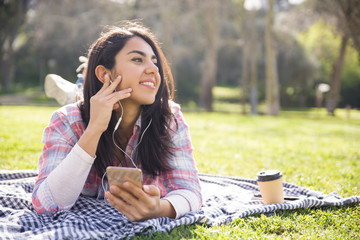 Joyful hipster girl in earphones resting outdoors