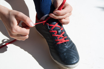 Closeup of hands of a child tying a soccer shoe on white background
