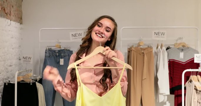 Young smiling woman tries on clothes and shows ok.