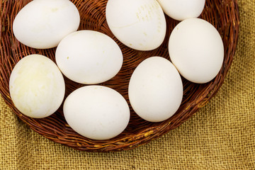 White chicken eggs in wicker basket on sackcloth background