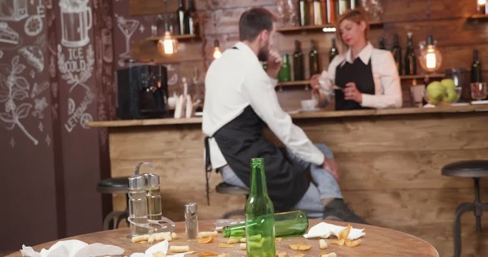 Restaurant staff neglecting their duties after restaurant is closed. Irresponsible restaurant staff chatting at the bar counter while they have to clean a dirty table.