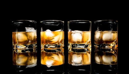 Whiskey with ice close up on a glass table isolated on a black background