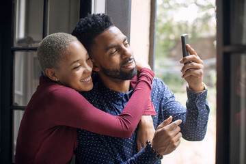Smiling couple taking selfie with smartphone