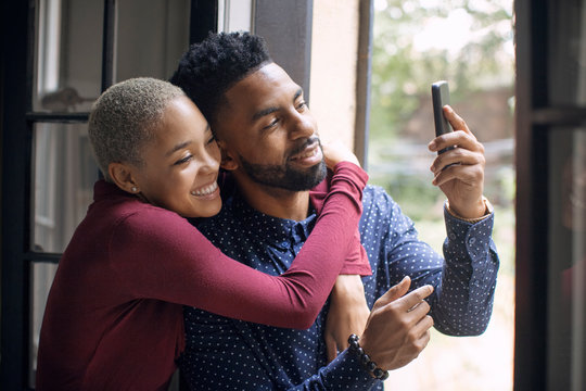 Smiling couple taking selfie with smartphone