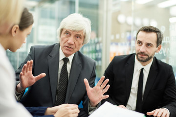 Fototapeta premium Group of business people discussing project in meeting, focus on senior businessman in foreground, copy space