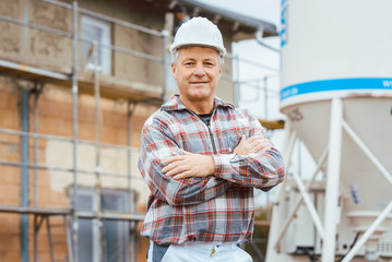 Obraz premium Proud plasterer standing in front of scaffold on construction site