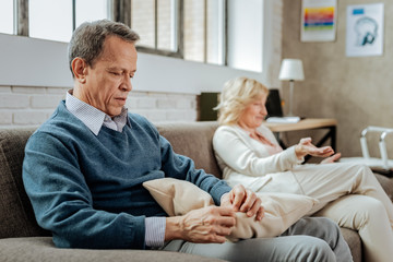Silent short-haired man sitting on couch with a pillow