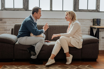 Adult sad couple sitting on couch in front of each other