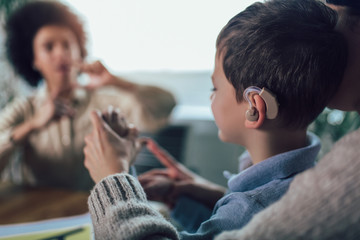 Smiling deaf boy learning sign language. Selective focus.