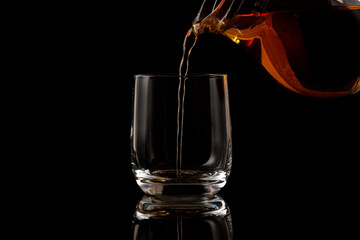 Brandy is poured into a glass on a black background