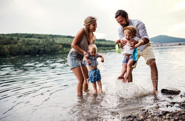 A young family with two toddler children outdoors by the river in summer.