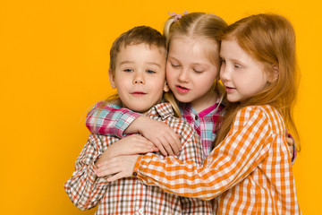 two little girls and boy on yellow background. cute children. friendship