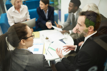 High angle view at multi-ethnic group of business people sitting in circle during meeting in...
