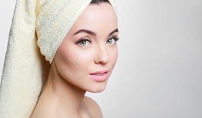 Portrait of young beautiful woman with healthy glow perfect smooth skin. Model with natural nude make up, with towel on head. Skincare, beauty, cosmetology concept. Gray background.