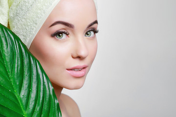 Portrait of young beautiful woman with healthy glow perfect smooth skin holds green tropical leaf....